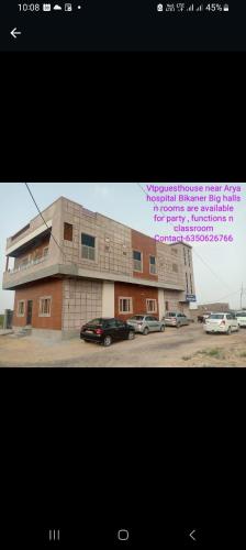 a building with cars parked in a parking lot at VTP Guest House in Bikaner