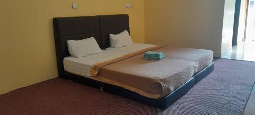 1 dormitorio con 1 cama grande y cabecero en Alia Tiara River and Beach Resort en Kota Bharu