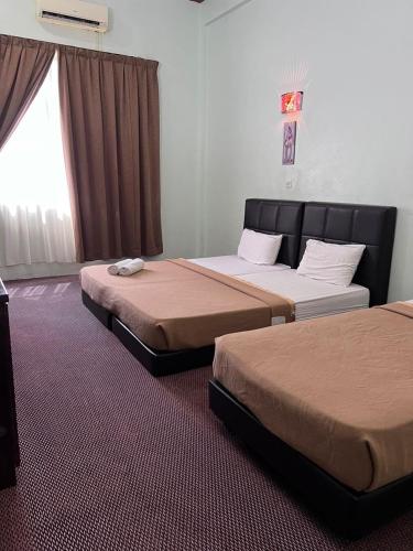 a bedroom with two beds and a window at Alia Tiara River and Beach Resort in Kota Bharu
