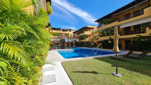a swimming pool with an umbrella next to a building at " Los Mangos" 2 bedroom 2 Bathroom appartment at walking distance from the beach in Zihuatanejo