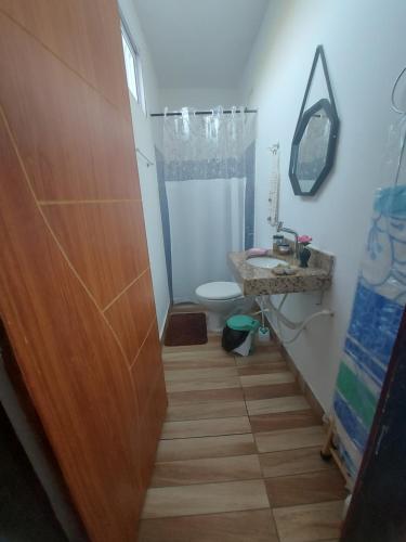 a bathroom with a toilet and a wooden door at Lugar tranquilo e aconchegante in Tibau do Sul