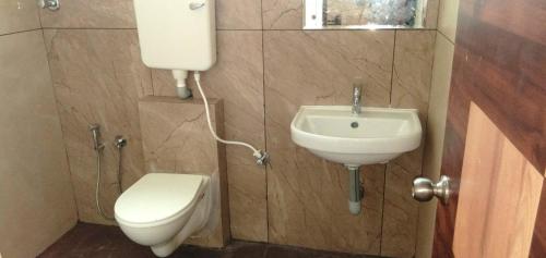 a small bathroom with a toilet and a sink at Hotel Rays Inn and Pegs Family Restaurant in Dharmastala