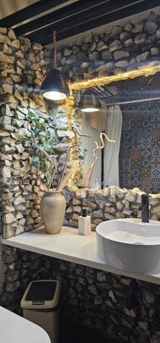 La salle de bains est pourvue d'un lavabo et d'un mur en pierre. dans l'établissement Chambao Maldives, à Guraidhoo