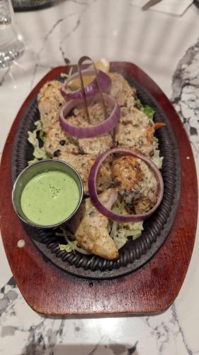 a plate of food on a wooden plate with onions and sauce at Hotel Rays Inn and Pegs Family Restaurant in Dharmastala