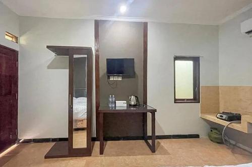 a room with a bed and a table with a mirror at Villa Kampoeng City Wonosalam Mitra RedDoorz in Jombang