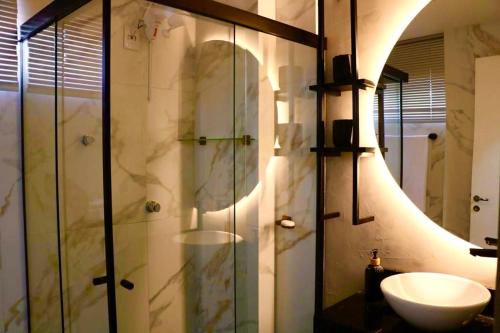 uma casa de banho com um lavatório e um chuveiro com um espelho. em Lindo apto 2 quartos quadra mar no Balneário Camboriú