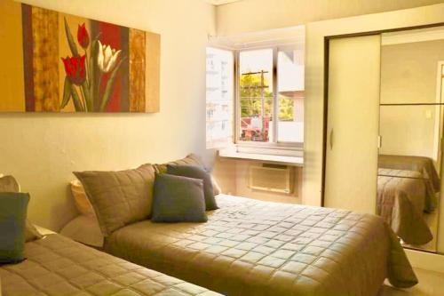 um quarto com uma cama, um sofá e uma janela em Lindo apto 2 quartos quadra mar em Balneário Camboriú