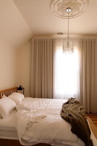 a bedroom with a bed and a chandelier and a window at Hazel House Goulburn in Goulburn
