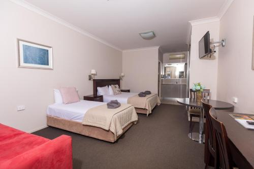 Highfields Motel Toowoomba في Highfields: غرفة فندقية بسريرين وطاولة