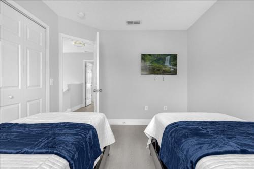 two beds in a room with white walls at 4 Bedrooms 35 Bathrooms Lake Berkley 938 Pt in Kissimmee
