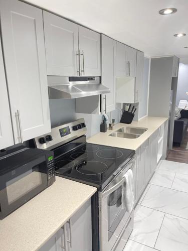 a kitchen with white cabinets and a stove top oven at Cozy basement in Brampton in Brampton