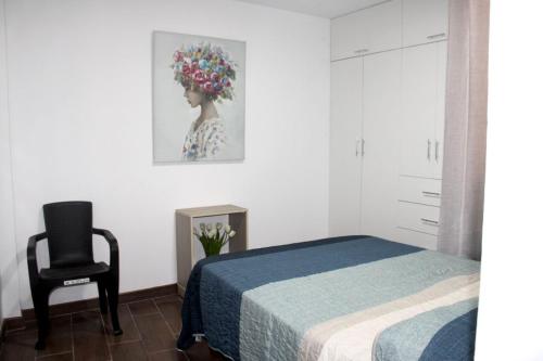 a bedroom with a bed and a chair and a painting at Departamento en Chiclayo Peru Las Brisas de Cix in Chiclayo