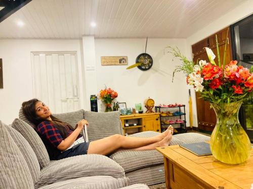 a woman sitting on a couch in a living room at The Blackberry Cottage in Nuwara Eliya
