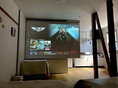 a large screen with a movie on it in a room at 川の音を聴きながら非日常体験を-伊豆の川辺に佇む小さなアパート-一人旅歓迎 in Izu