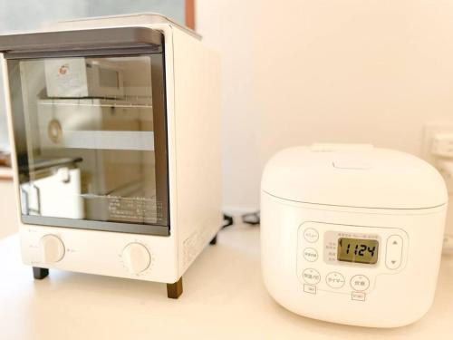 a microwave sitting on a counter with a clock on it at 川の音を聴きながら非日常体験を-伊豆の川辺に佇む小さなアパート-一人旅歓迎 in Izu