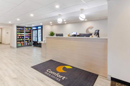 an office lobby with a reception counter with a company sign on it at Comfort Inn & Suites in Beaver Dam