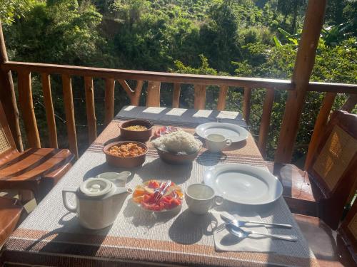 a table with bowls and plates of food on a balcony at Ella Rock Grun Cottage in Ella