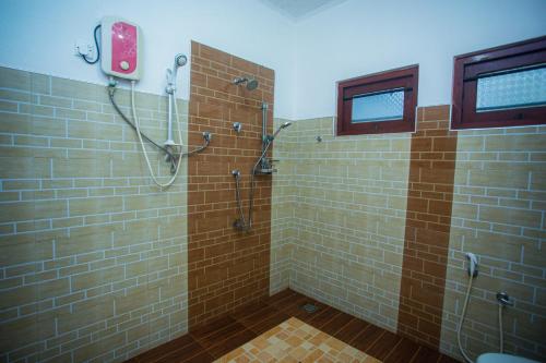 y baño con ducha y azulejos marrones. en Villa Greenjay Ahangama, en Ahangama
