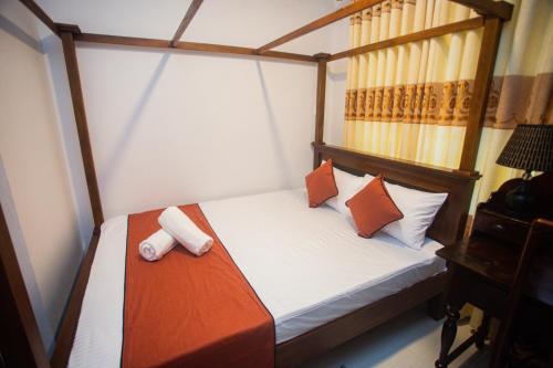 a small bedroom with a bed with orange and white pillows at Villa Greenjay Ahangama in Ahangama