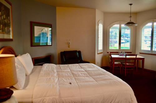 - une chambre avec un grand lit blanc et un bureau dans l'établissement Anaco Bay Inn, à Anacortes