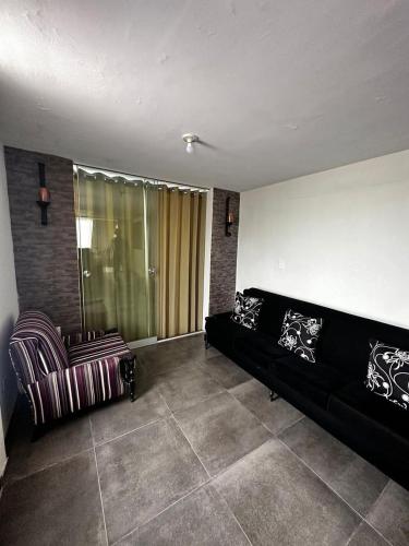 a living room with a black couch and a chair at Casa villa Eru in Pisco