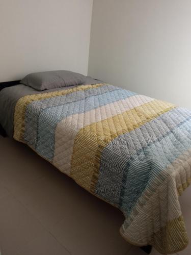 a bed with a colorful blanket on top of it at Casa villa Eru in Pisco