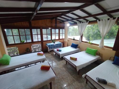 a room with three beds and windows and a table at wellassa homestay in Badulla