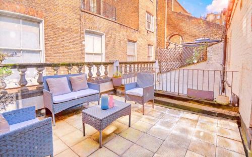 un patio con sillas y mesas en un balcón en TOWNHOUSE with ROOFTOP by Hyde Park, en Londres