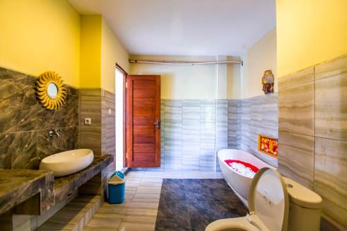a bathroom with a tub and a toilet and a sink at Asri Sari Villa Ubud in Ubud