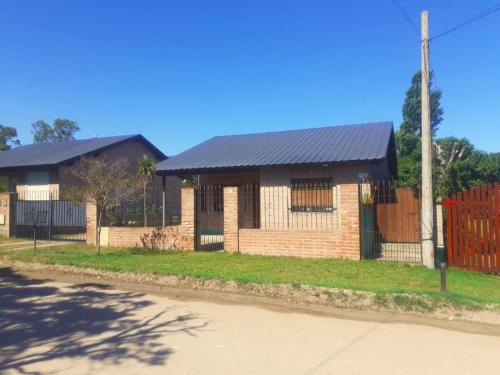 a brick house with a black roof on a street at Casa Monte Hermoso del Este in Monte Hermoso