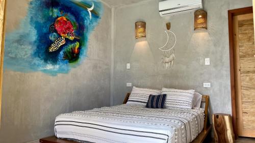 - une chambre avec un lit orné d'une peinture murale dans l'établissement SHANTI SURF CAMP, à El Paredón Buena Vista