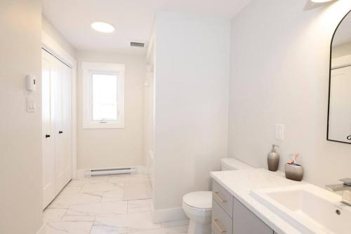 a white bathroom with a toilet and a sink at Luxury Room in a House. in Moncton