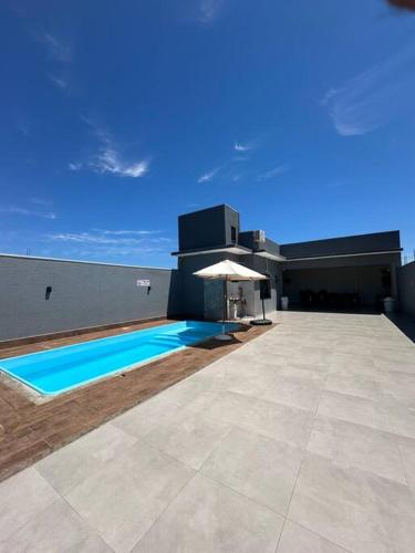 a house with a swimming pool and an umbrella at LAR Espaço Lazer in Foz do Iguaçu