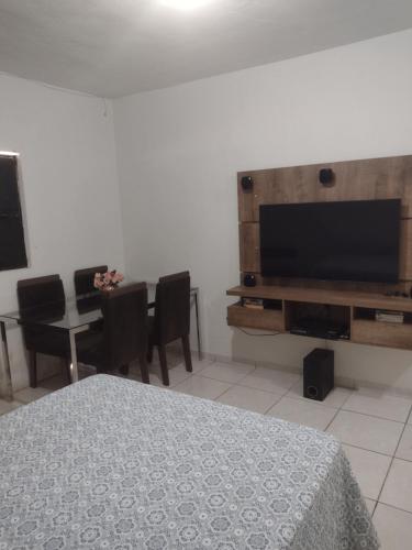 um quarto com uma televisão e uma mesa com cadeiras em Conforto simples em Maceió