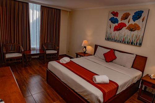 una camera d'albergo con letto, scrivania e finestra di PURI DIBIA HOTEL a Kuta
