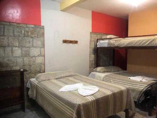 2 camas en una habitación con paredes rojas y blancas en Hotel Marjenny, en Copan Ruinas