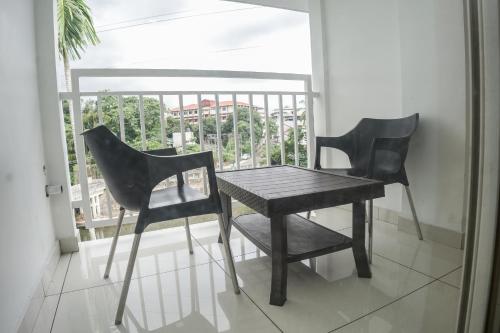 2 schwarze Stühle und ein Tisch auf dem Balkon in der Unterkunft HOTEL LETS STAY in Ernakulam