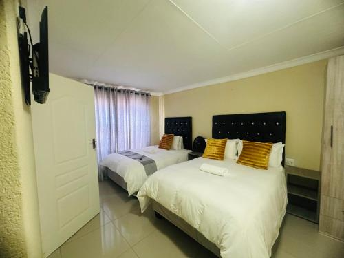 a bedroom with two beds and a door to a room at MBT Guesthouses in Ga-Mothiba