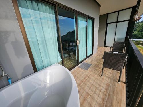 a bath tub in a bathroom with a balcony at So View Phuket Resort in Ban Sam Kong