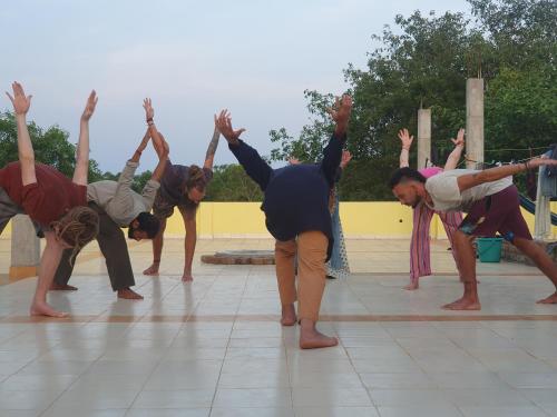 a group of people doing a yoga pose on a tile floor at Unearth Hostel (Pondicherry) in Auroville