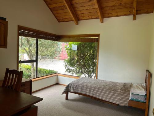 a bedroom with a bed and a large window at Rosie's Farmhouse in Pukekohe East