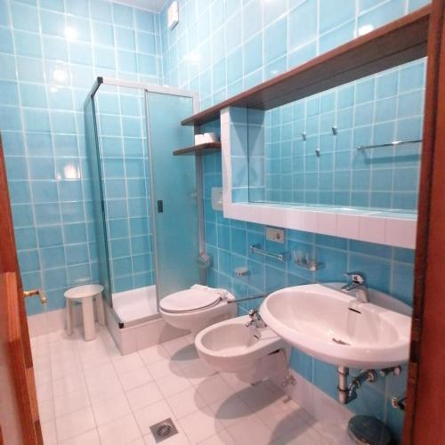 ein blau gefliestes Bad mit WC und Waschbecken in der Unterkunft appartamento 022G Hotel Ploner in Toblach