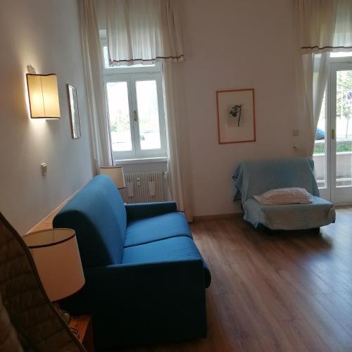 ein Wohnzimmer mit einem blauen Sofa und einem Stuhl in der Unterkunft appartamento 022G Hotel Ploner in Toblach