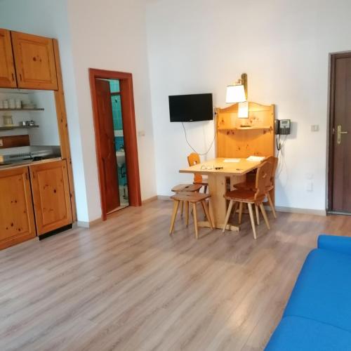 un soggiorno con tavolo, sedie e TV di appartamento 022G Hotel Ploner a Dobbiaco
