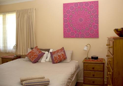 a bedroom with a bed and a pink painting on the wall at It's on Walnut in Mildura