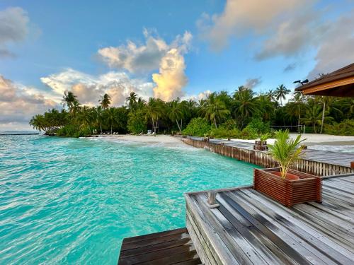 vistas a una playa con terraza de madera y agua en Fiyavalhu Resort Maldives en Mandhoo