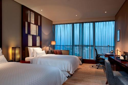 um quarto de hotel com duas camas e uma secretária em The Westin Beijing Chaoyang em Pequim