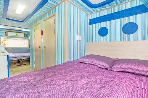 a bedroom with a purple bed and blue walls at Gangneung C-cloud caravan in Gangneung