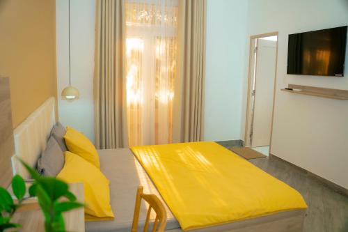 a living room with a yellow blanket on a bed at Lá Homestay in Ap My Quo