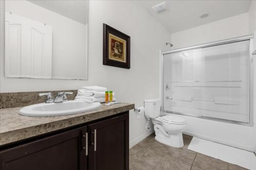 Baño blanco con lavabo y aseo en 6 Bedroom 4,5 Baths Crystal Cove Resort 957 Eg, en Kissimmee